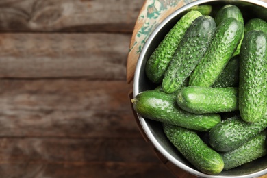 Photo of Bowl with ripe fresh cucumbers on table, top view