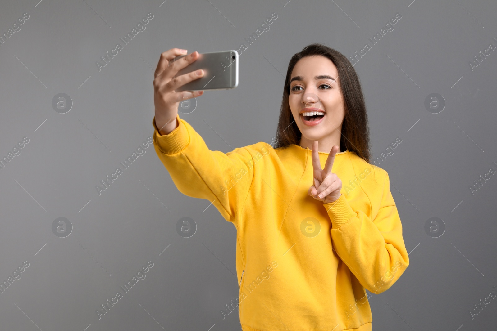 Photo of Attractive young woman taking selfie with phone on color background