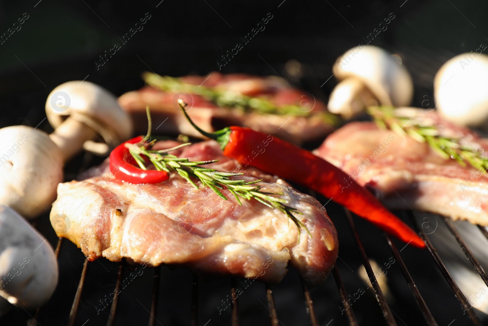 Photo of Cooking meat, chilli peppers and mushrooms on barbecue grill outdoors, closeup