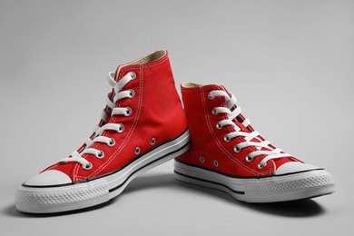 Photo of Pair of new stylish red sneakers on light grey background