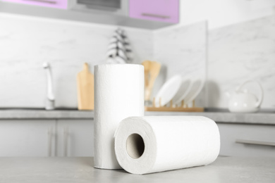 Photo of Rolls of paper towels on light grey table in kitchen