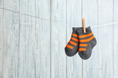 Photo of Pair of socks on laundry line against wooden background, space for text. Baby accessories