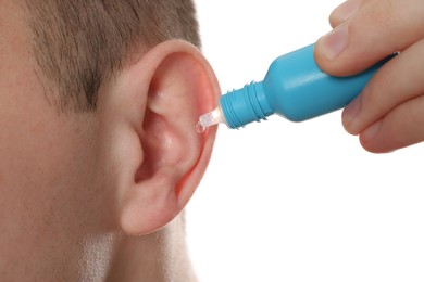 Photo of Man using ear drops on white background, closeup