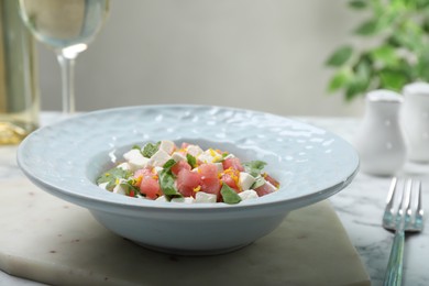 Photo of Delicious salad with watermelon, arugula and feta cheese served on white marble table