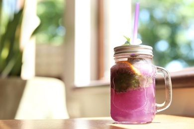 Photo of Refreshing natural lemonade with mint in mason jar on table. Detox drink