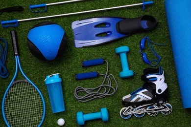 Photo of Different sport equipment on green grass, flat lay