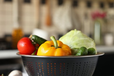 Photo of Metal colander with different wet vegetables on table, closeup