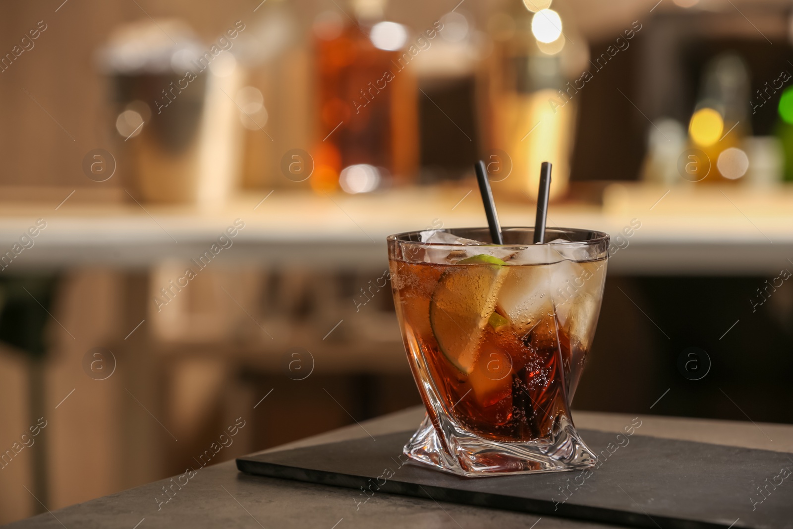 Photo of Cuba Libre cocktail on table in bar. Space for text