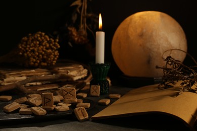 Photo of Composition with wooden runes and old books on black table