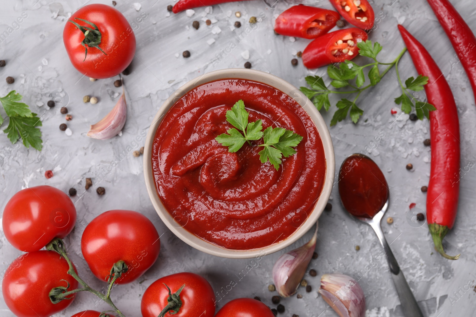 Flat lay composition with organic ketchup in bowl on grey textured table. Tomato sauce Photo of Flat lay composition with organic ketchup in bowl on grey textured table. Tomato sauce