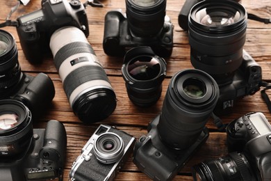 Photo of Modern cameras on wooden table, closeup. Professional photography equipment