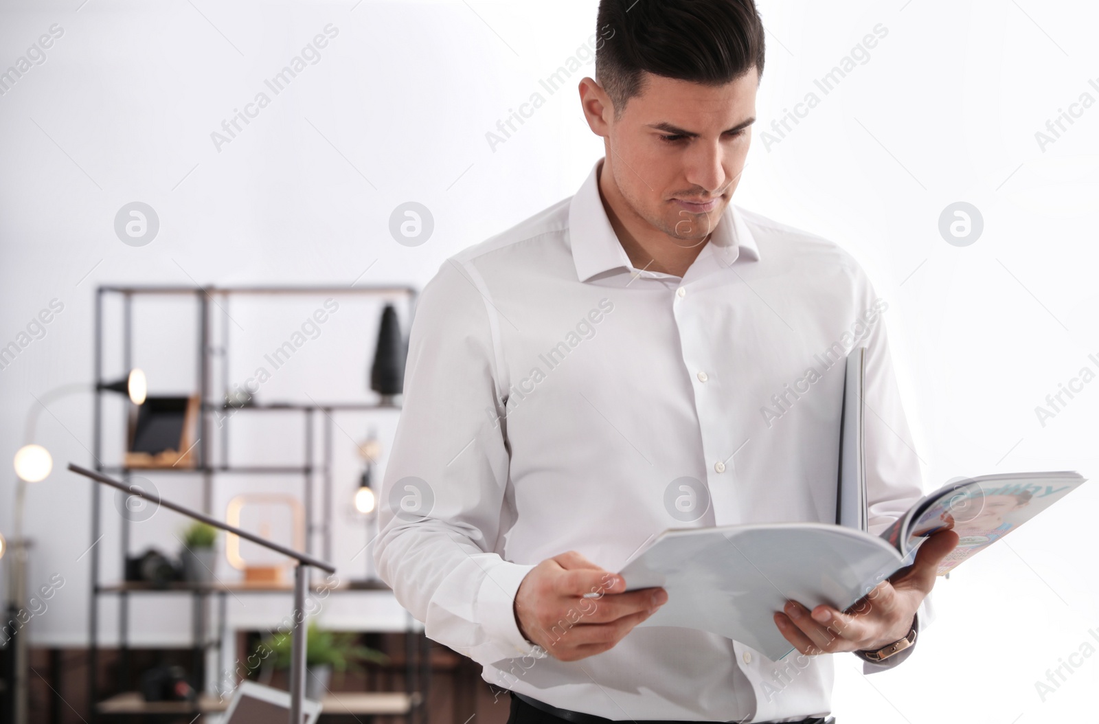 Photo of Man reading magazine in office. Space for text