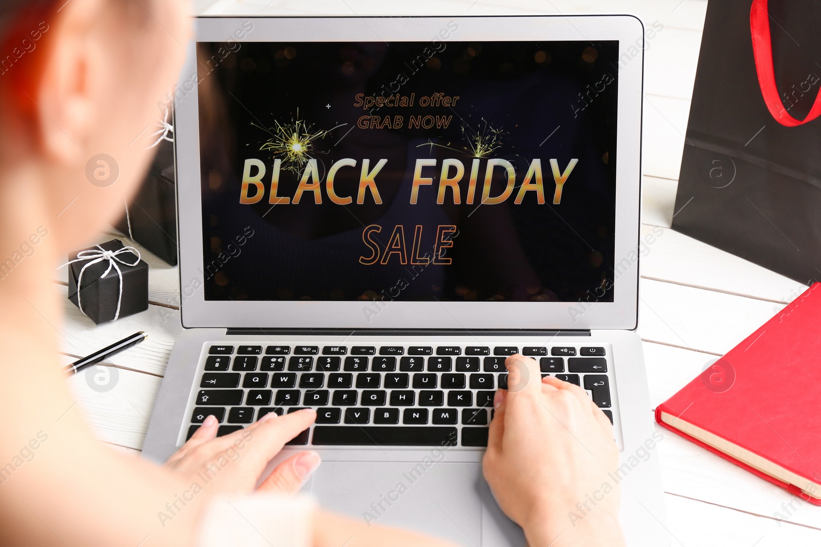 Photo of Woman shopping online using laptop at white wooden table, closeup. Black Friday Sale