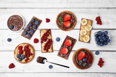 Photo of Many fresh rye crispbreads and rusks with different toppings on white wooden table, flat lay