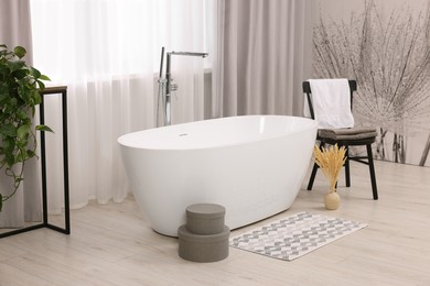 Photo of Stylish bathroom interior with soft bath mat and tub