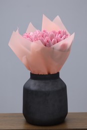 Photo of Bouquet of beautiful pink tulips in vase on wooden table against light grey background