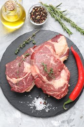Photo of Fresh raw beef cut with different spices on light grey textured table, flat lay