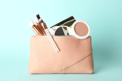 Photo of Cosmetic bag with makeup products and beauty accessories on light blue background
