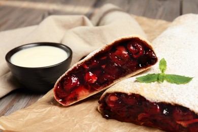 Photo of Delicious strudel with cherries served on wooden table, closeup