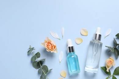 Photo of Flat lay composition with cosmetic serums on light blue background, space for text