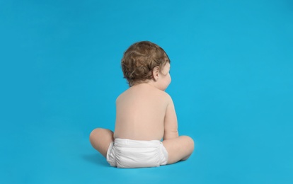 Photo of Cute little baby in diaper on light blue background. Space for text