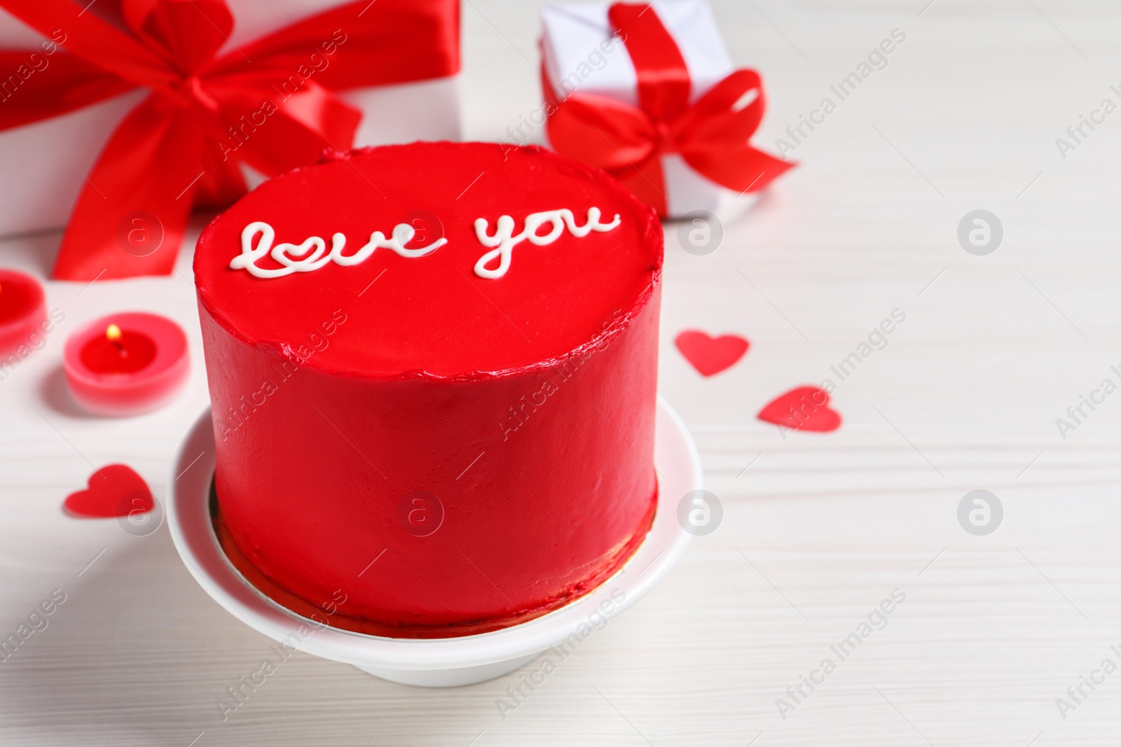 Photo of Bento cake with text Love You, gift boxes, candles and paper hearts on white wooden table, space for text. St. Valentine's day surprise