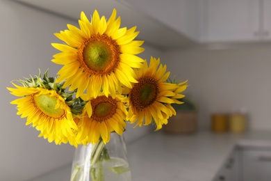 Photo of Vase with beautiful yellow sunflowers in kitchen, space for text