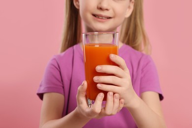 Photo of Cute little girl with glass of fresh juice on pink background, closeup
