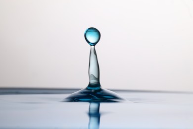Photo of Splash of clear water with drop on light background, closeup
