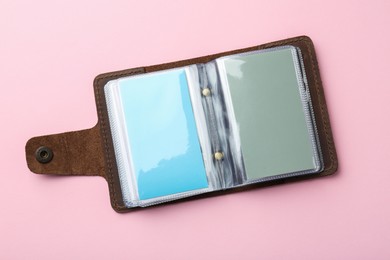 Photo of Leather business card holder with blank cards on pink background, top view