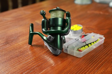 Photo of Fishing tackle. Spinning reel, lures and bait on wooden table, closeup