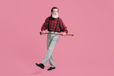 Photo of Senior man with walking cane on pink background