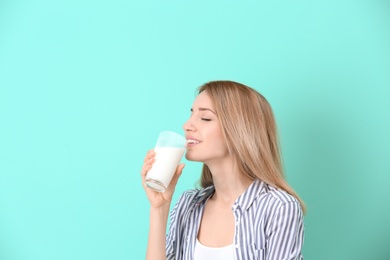 Photo of Beautiful young woman drinking milk on color background