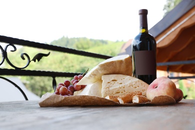 Photo of Bunch of grapes, wine, cheese and peaches on wooden table. Space for text