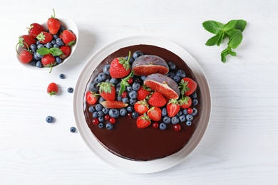 Photo of Fresh delicious homemade chocolate cake with berries on light table, flat lay