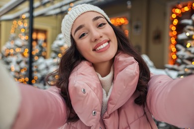 Photo of Portrait of smiling woman taking selfie on city street in winter