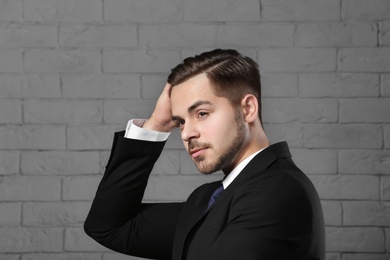 Photo of Portrait of young man with beautiful hair on brick wall background