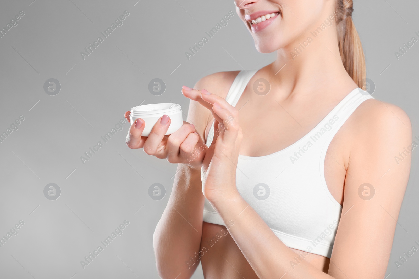 Photo of Young woman with jar of body cream on color background