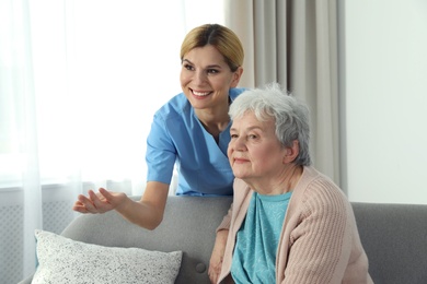 Photo of Nurse with elderly woman indoors. Assisting senior people