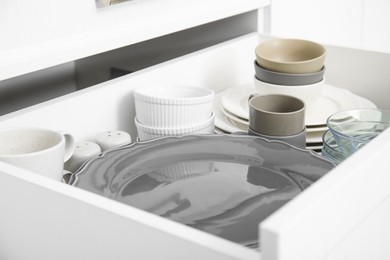 Photo of Open drawerkitchen cabinet with different dishware, closeup