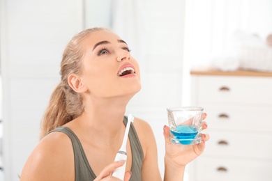 Photo of Woman rinsing mouth with mouthwash in bathroom. Teeth care