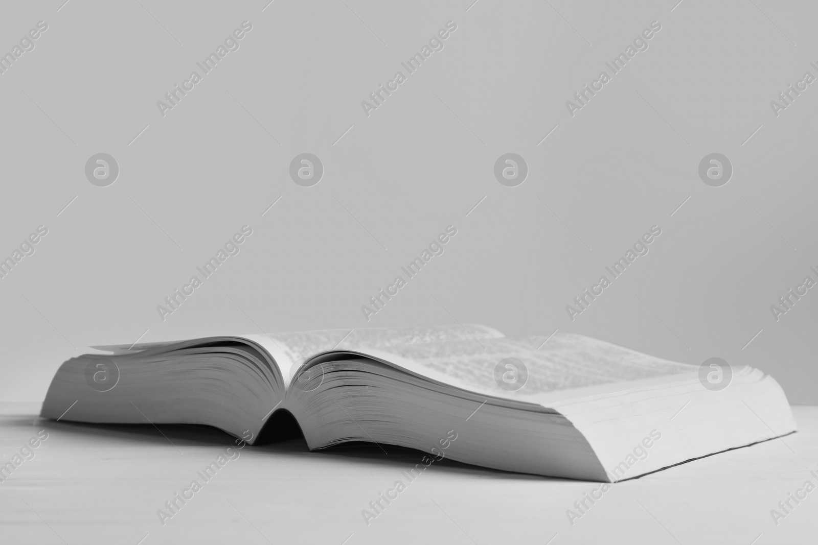 Photo of Open Bible on white wooden table, space for text. Religious book