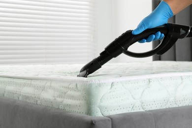 Photo of Woman disinfecting mattress with vacuum cleaner indoors, closeup. Space for text
