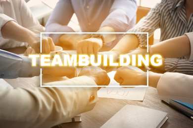Image of People putting hands together at table. Teambuilding concept