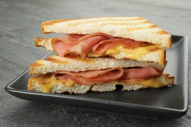 Photo of Tasty sandwiches with ham and melted cheese on grey textured table, closeup