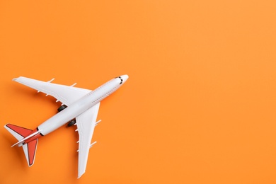Photo of Toy airplane on orange background, top view. Space for text