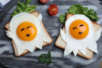 Photo of Halloween themed breakfast served on black table, flat lay. Tasty toasts with fried eggs in shape of ghost
