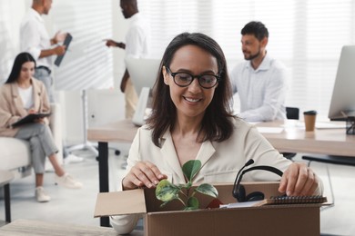 Photo of New coworker unpacking box with personal items at workplace in office
