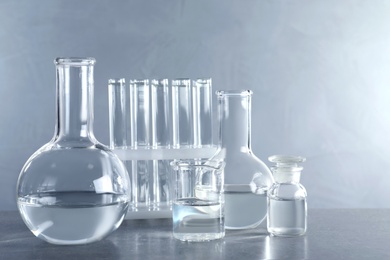 Photo of Laboratory glassware with liquid samples for analysis on table against grey background