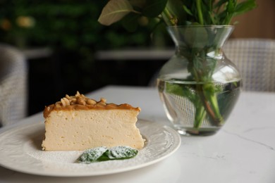 Photo of Tasty dessert and vase with flowers on white table indoors